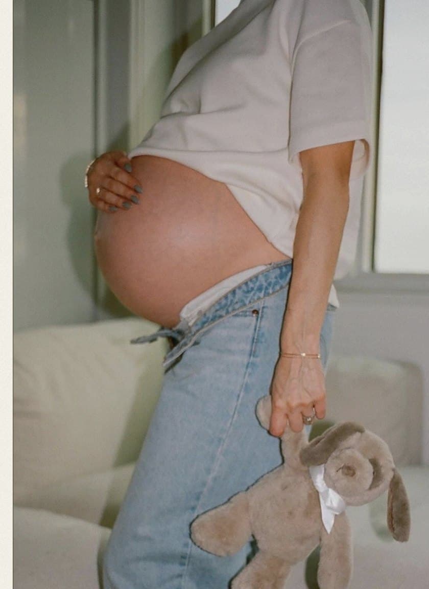 Maternidad retratada con luz natural y tonos suaves.